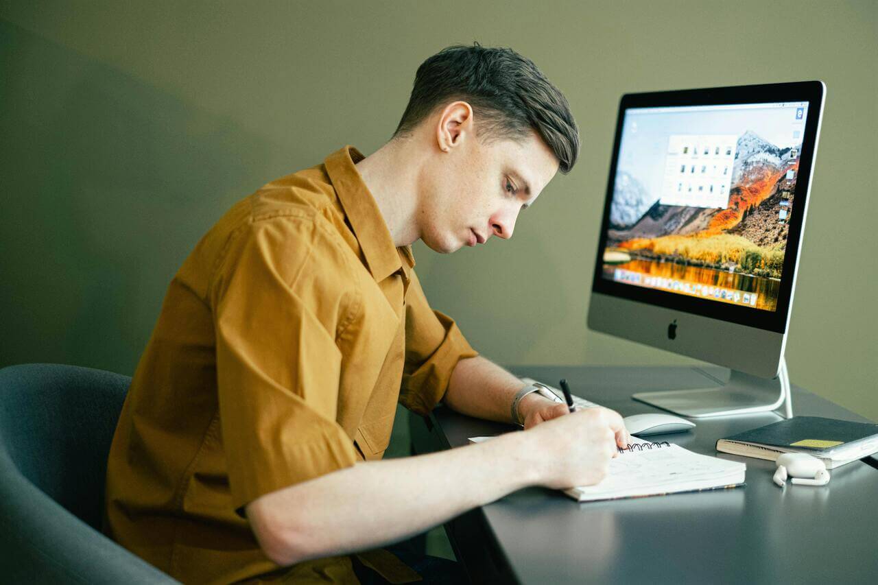 Boy Writing in Notebook at Desk 